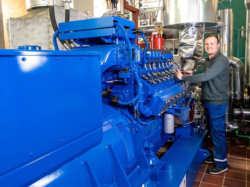 Energieanlagenfachmann Normann Brüsch (Vereinigte Stadtwerke, Ratzeburg) vor dem neuen MWM Gasmotor