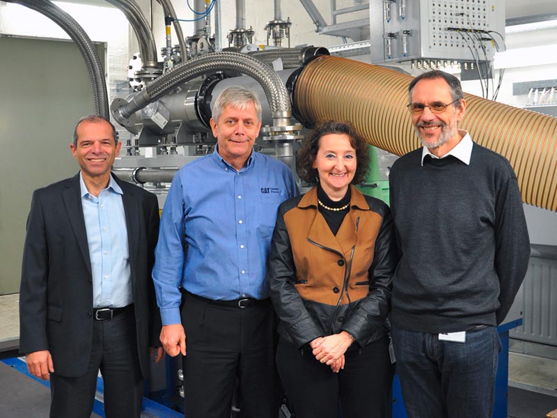 Wilhelm Müller (General Manager Research & Development), Willy Schumacher (Managing Director), Ilona Beichert (Leiterin Entwicklungsprüfstände), und Karl Stellwagen (Manager New Engine Technologies) vor dem Entwicklungsprüfstand des Einzylinder-Gasmotors (v.l.n.r.)